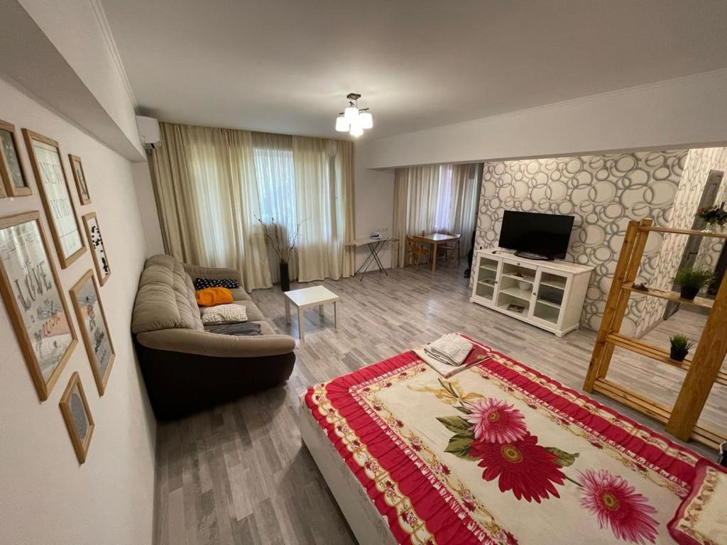 sala de estar con sofá y TV en Квартира, en Almaty