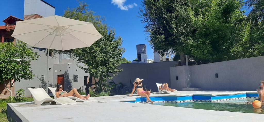 um grupo de pessoas sentadas numa piscina com um guarda-chuva em Apart y Suite Portal del Luz em Mina Clavero