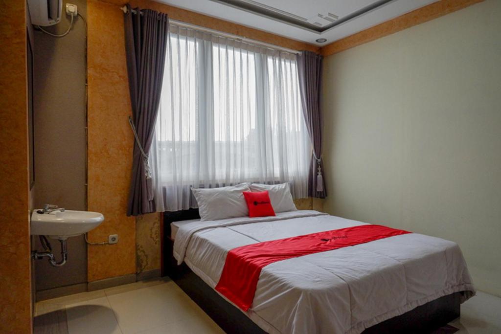 a bedroom with a bed and a sink and a window at RedDoorz near MM UGM in Yogyakarta