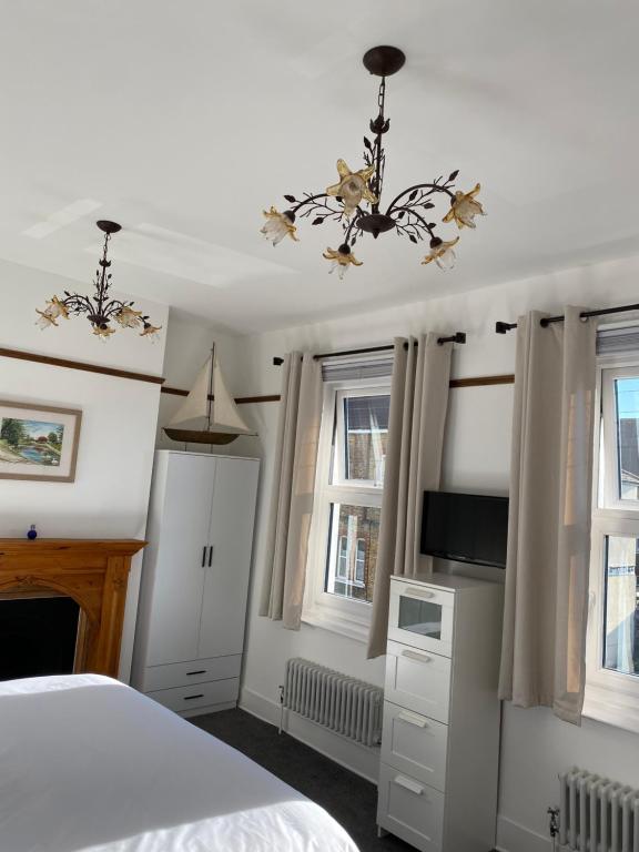 a bedroom with a bed and a chandelier and windows at Cosy 2 Bedroom House -2022 & 2023 Award Winner! in Ramsgate