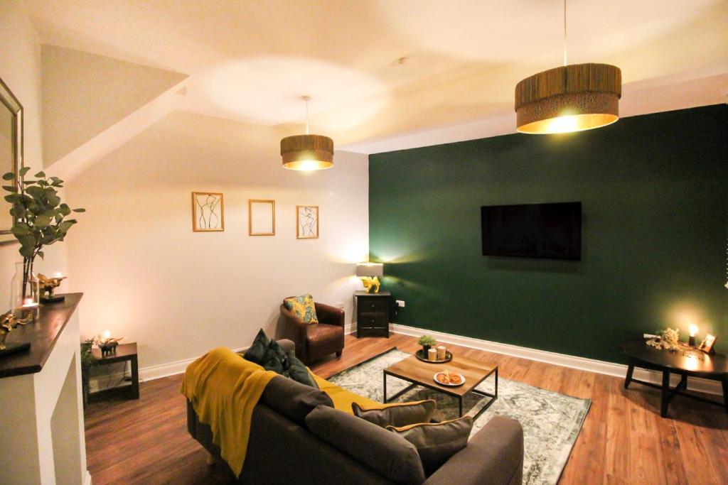 a living room with a couch and a green wall at 3 Bedroom City Centre Townhouse in Nottingham