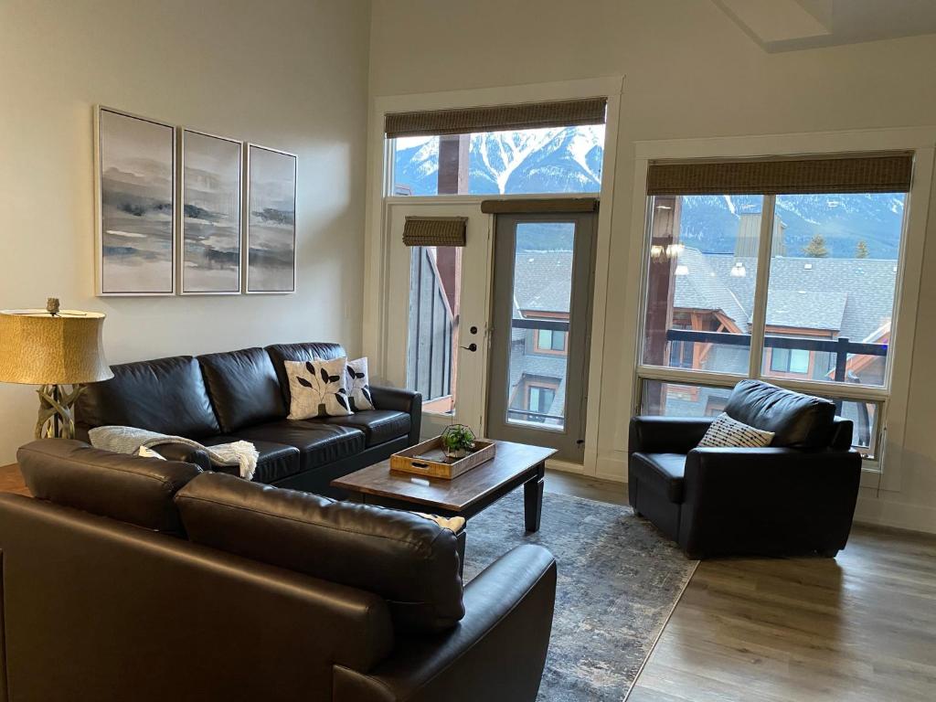 a living room with a leather couch and a table at Spectacular Penthouse With Amazing Views, Indoor Pool and Hot tub in Canmore