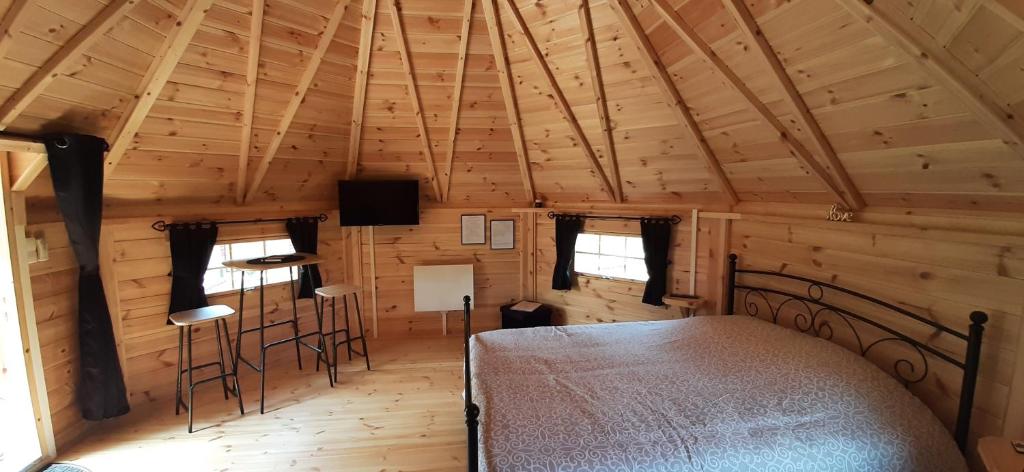 - une chambre dans une cabane en rondins avec un lit et des tabourets dans l'établissement Kota Scandinave avec son bain nordique privatif - Gîte du Moulin 62130 Pierremont, à Pierremont