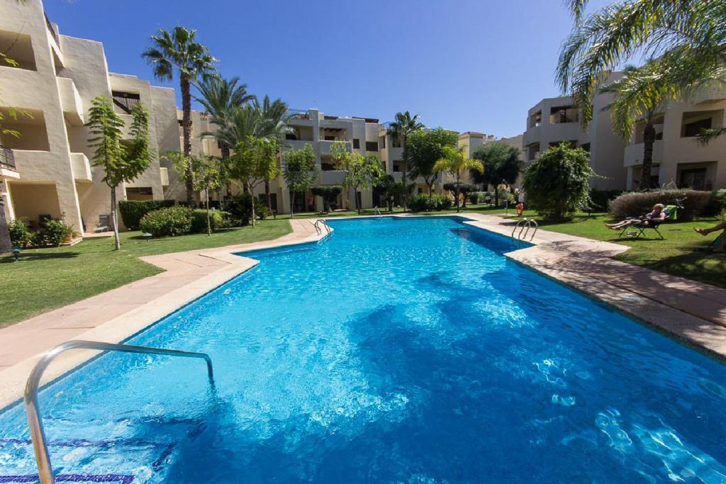 a large blue swimming pool in front of a building at RODA Golf & Beach Resort Wonderful Ground Floor Apartment in Roda