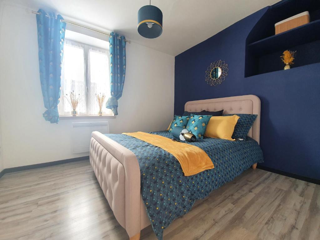 1 dormitorio con 1 cama con pared azul en Appartement chaleureux en Oignies