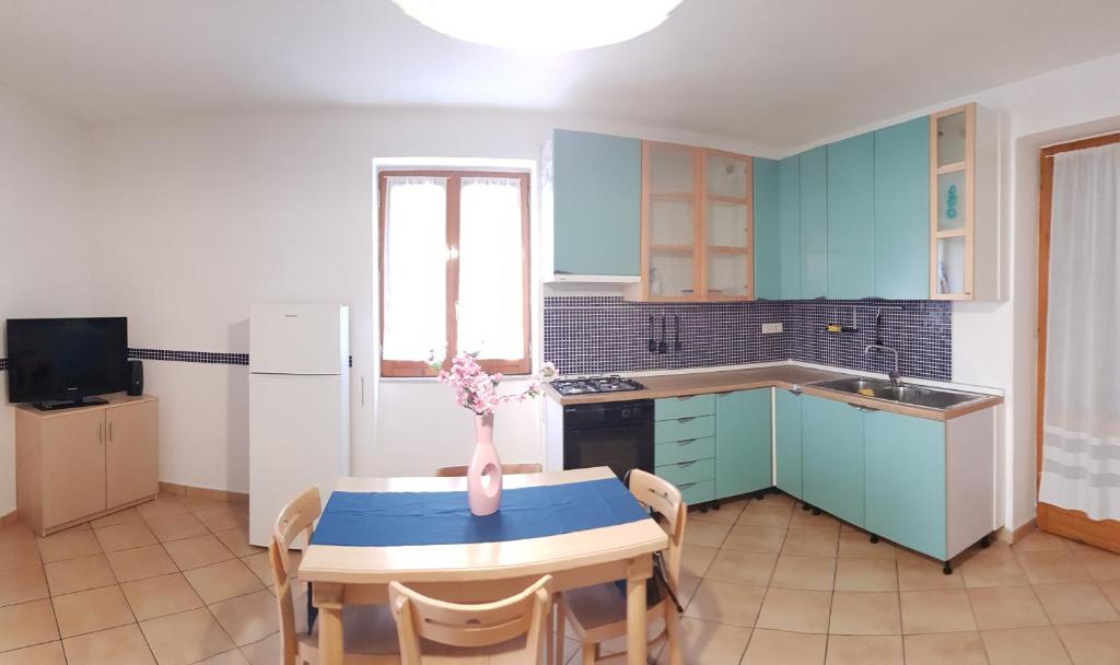 een keuken met blauwe kasten en een tafel met een vaas erop bij Casa Ambra in Cava deʼ Tirreni