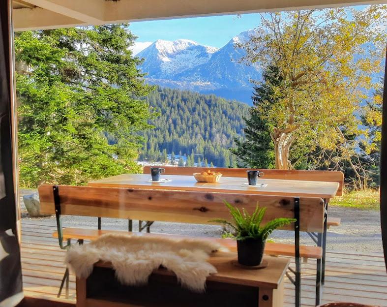 une table sur une terrasse avec vue sur la montagne dans l'établissement Chaleureux appartement aux pieds des pistes, à Chamrousse