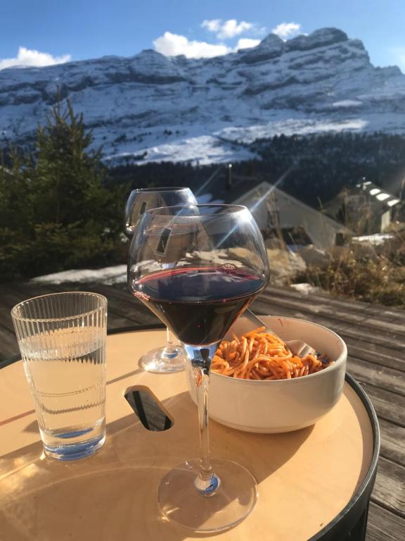 a glass of wine and a bowl of food on a table at MAGNIFIQUE APPARTEMENT AVEC TERRASSE et VUE IMPRENABLE SUR LE CIRQUE DE FLAINE, 2 chambres et coin montagne, 6 personnes in Flaine