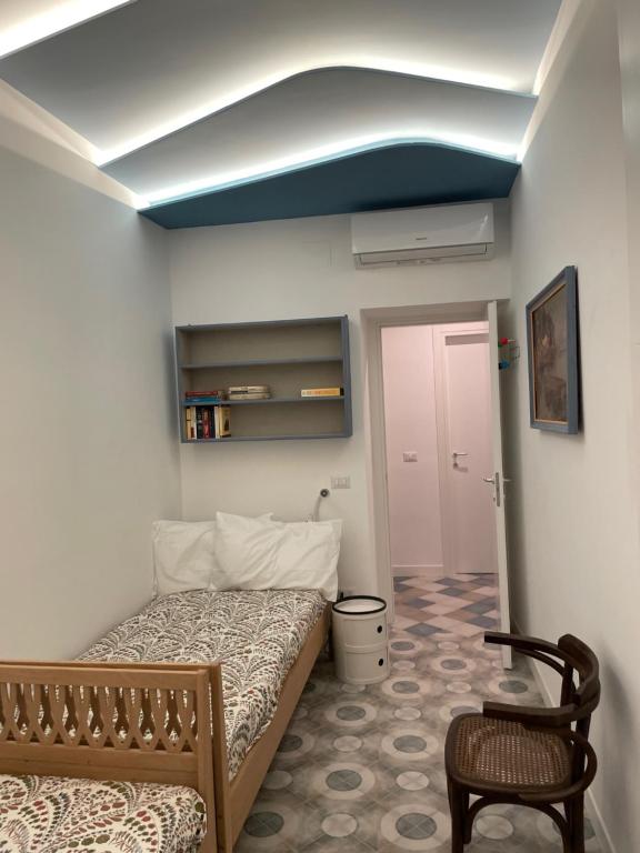 um pequeno quarto com uma cama e uma cadeira em Casa Luciano al San Carlo em Nápoles