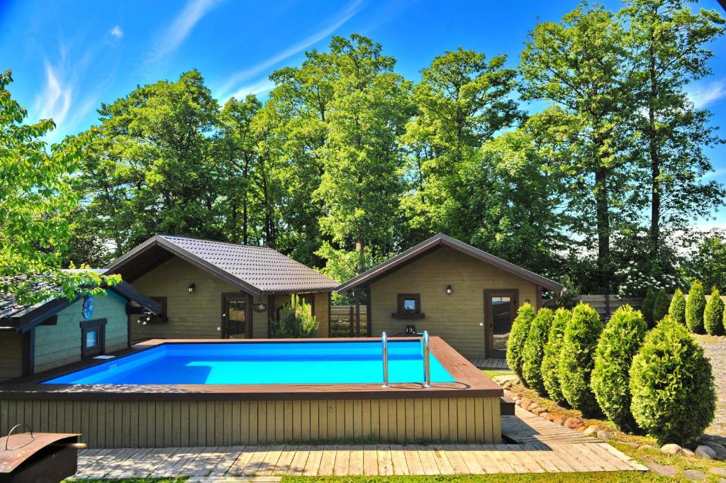 a swimming pool in front of a house at Resort Baure in Palanga