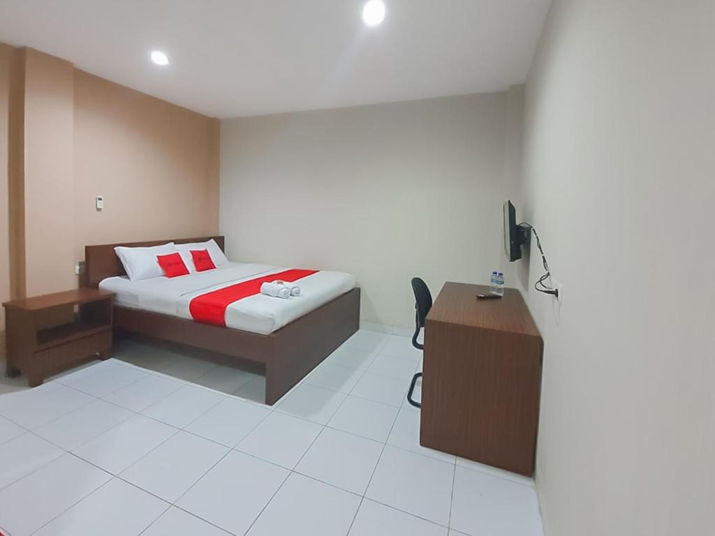 um quarto com uma cama e uma secretária. em RedDoorz Plus at Pelita Guest House Balikpapan em Balikpapan