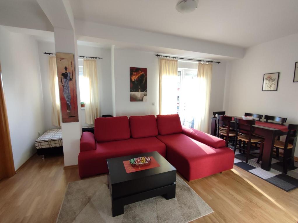 een woonkamer met een rode bank en een tafel bij Apartman Ana in Bosanska Gradiška