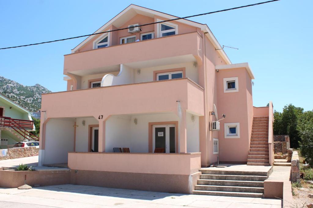 a pink house with stairs in front of it at Apartmens Leona in Karlobag