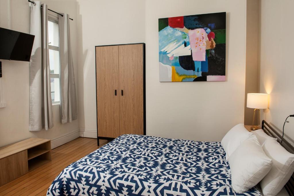 Un dormitorio con una cama azul y blanca y un armario en The Met Hotel, en Toowoomba
