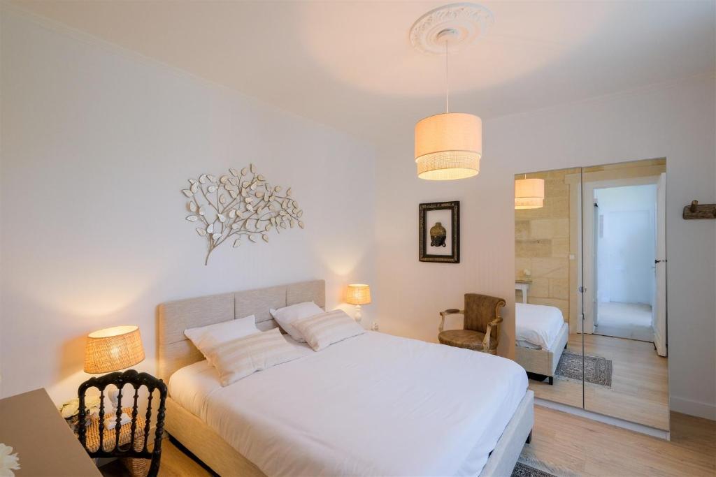 Schlafzimmer mit einem weißen Bett und einem Spiegel in der Unterkunft Les Suites d'Aliénor-Suite Acanthe in Pessac