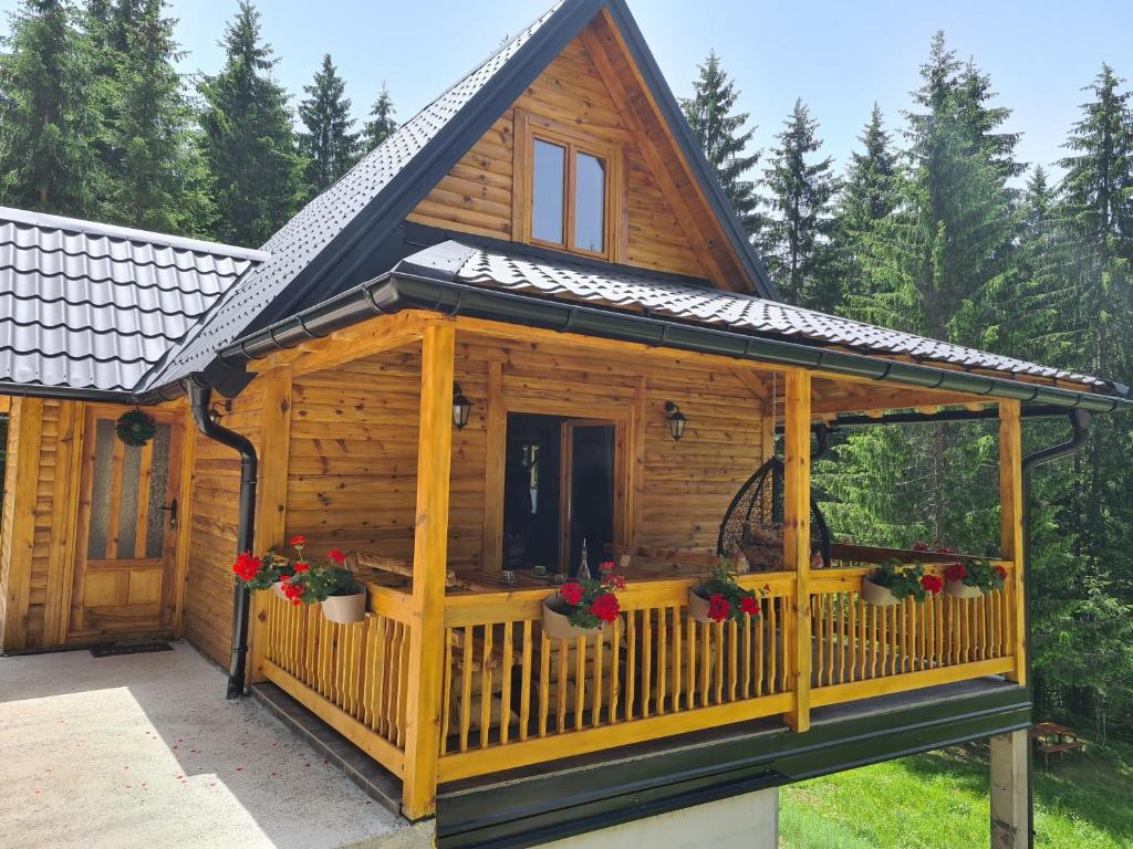 una cabaña de madera con porche y flores. en Brvnara Vukovine en Nova Varoš