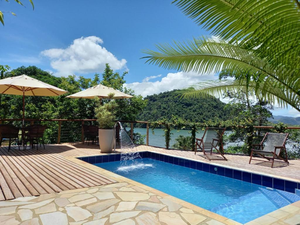 a swimming pool with a deck and a view of the water at Pousada Kaetê in Paraty
