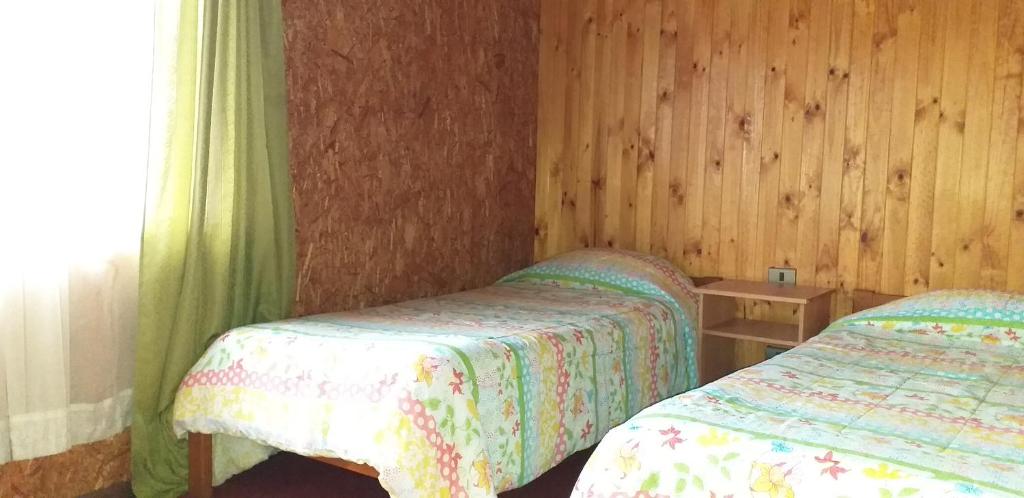 a bedroom with two beds and a window at Hospedaje Picoyo in Pucón