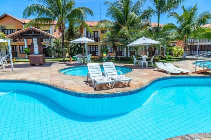 a swimming pool with chairs and umbrellas in a resort at Casa Moradas de Israel in Porto Seguro