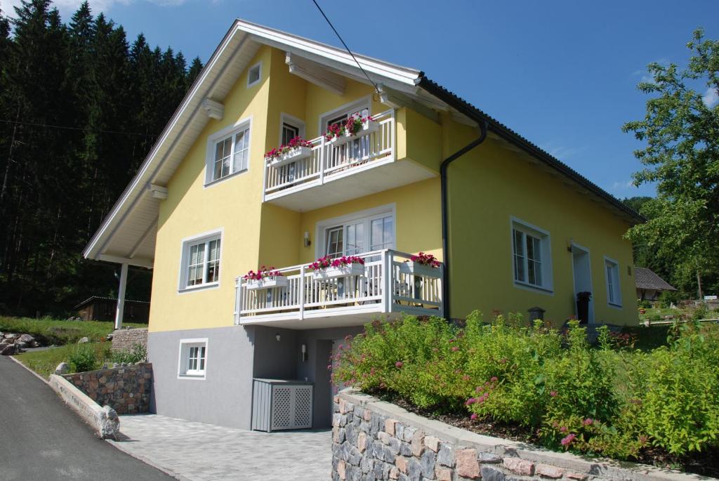 Casa blanca y amarilla con flores en los balcones en FeWo Burgstaller, en Tröpolach