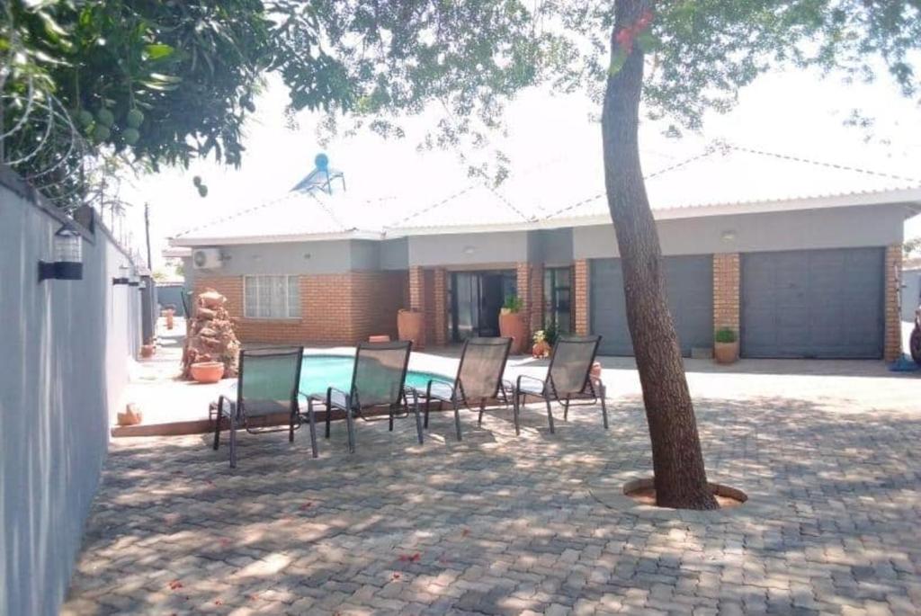 un groupe de chaises assises devant une maison dans l'établissement Chitova’s Guesthouse, à Victoria Falls