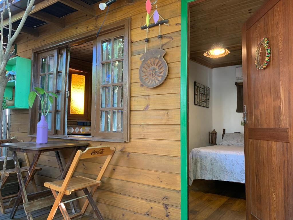 a room with a table and a bed and a window at Chale canto verde Villa Facioni in Palhoça