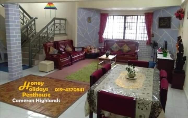 ein Wohnzimmer mit Sofas und einem Tisch. in der Unterkunft Honey Holiday Penthouse in Tanah Rata