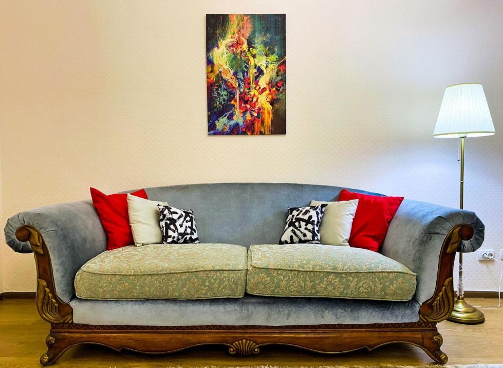 Трехкомнатные апартаменты в центре Левого Берега г.Нур-султан في أستانا: أريكة في غرفة معيشة مع لوحة على الحائط