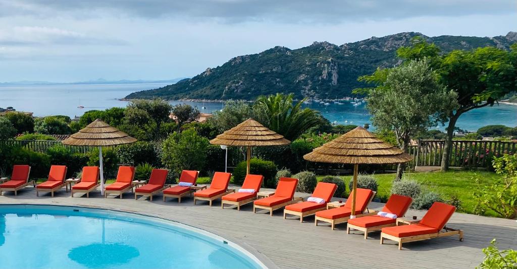 - une rangée de chaises et de parasols à côté de la piscine dans l'établissement Hôtel Alivi Di Santa Giulia, à Porto-Vecchio