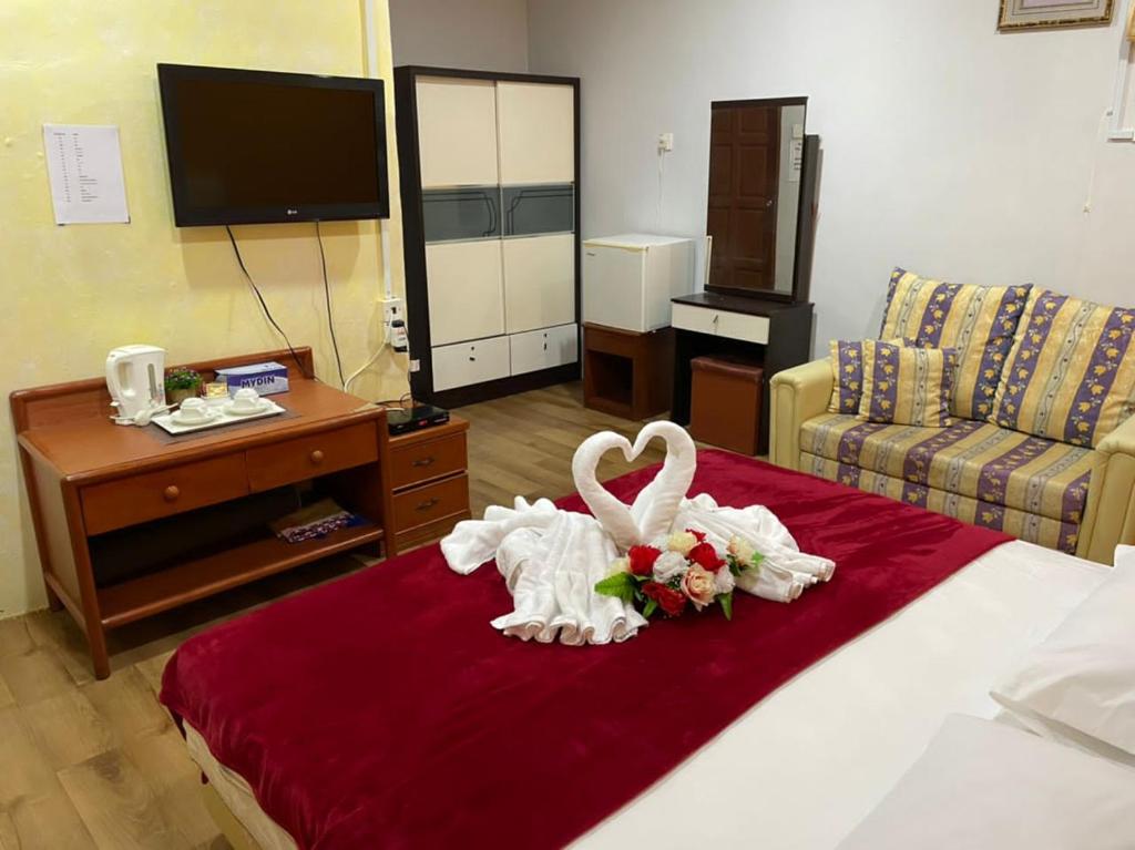 a hotel room with a bed with a bouquet of flowers at Samudera Hotel in Kampung Kuala Besut