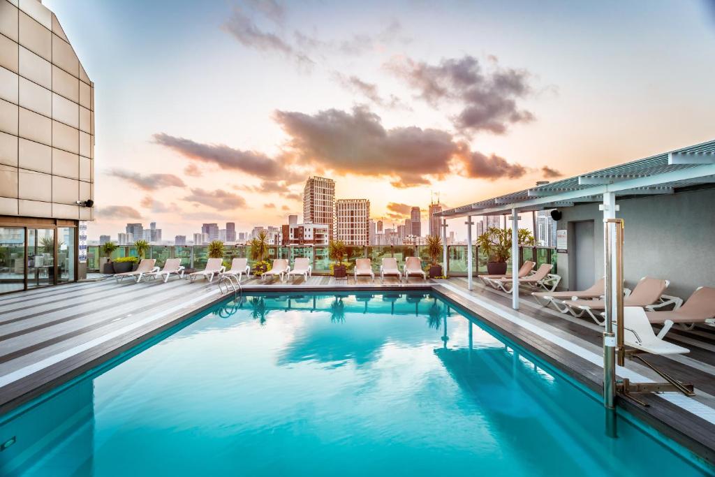 a swimming pool on the roof of a building with a city skyline at Roxon Urban Ramat Gan in Ramat Gan