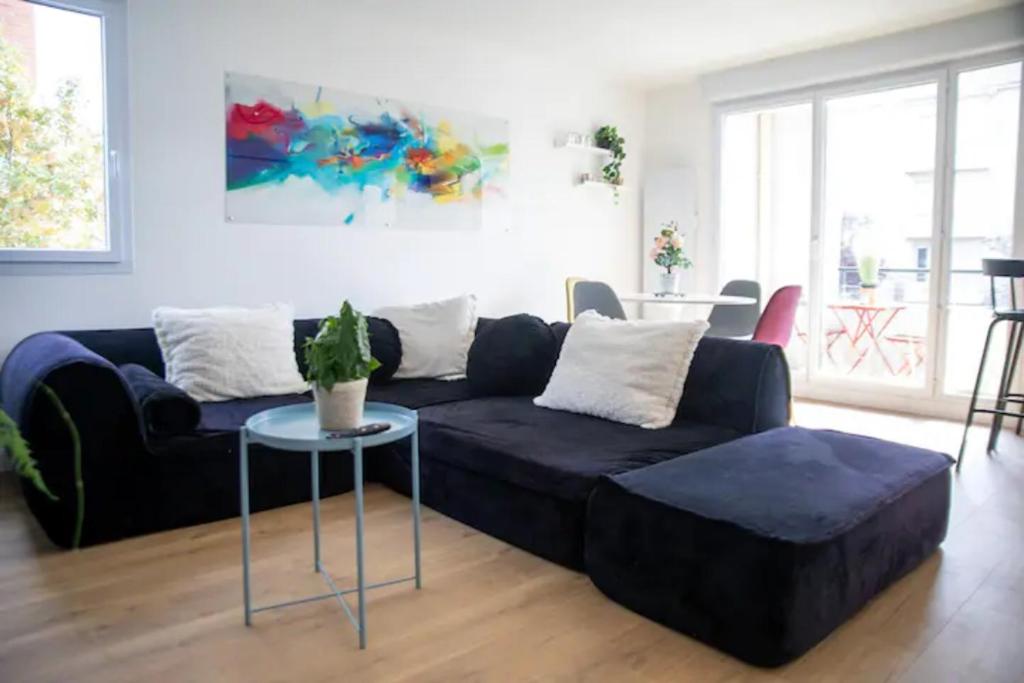 ein Wohnzimmer mit einem schwarzen Sofa und einem Tisch in der Unterkunft LES 2 LIONS moderne confort proche transports in Tours