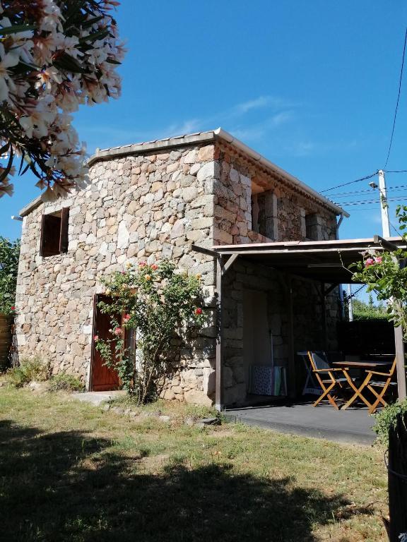 a stone house with a porch and a patio at Sarrola-Carcopino Gîte en Pierre in Sarrola-Carcopino