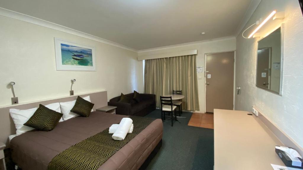 ein Hotelzimmer mit einem Bett und einem Wohnzimmer in der Unterkunft Sapphire City Motor Inn in Inverell