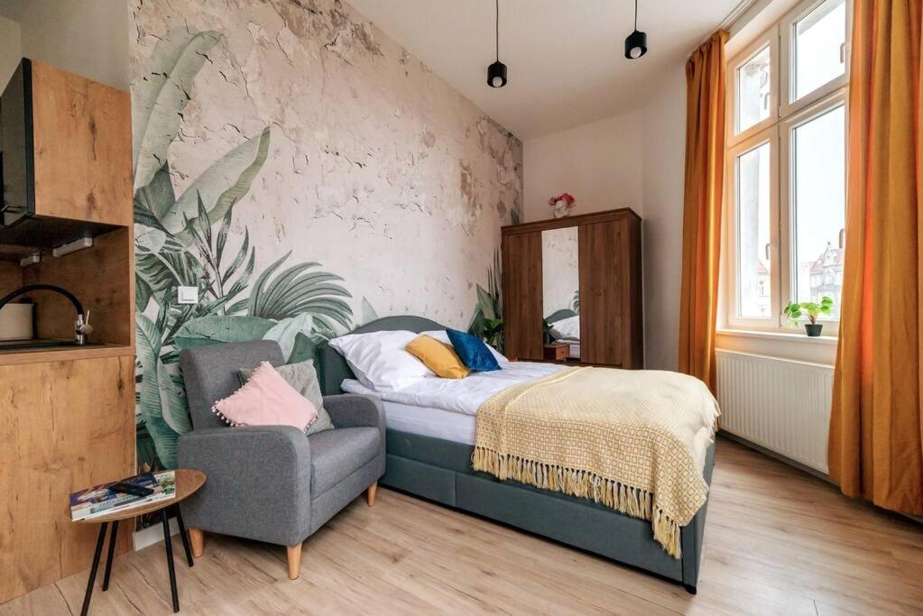a bedroom with a bed and a chair at Cozy, Small Studio.Great location / Mała Kawalerka in Szczecin
