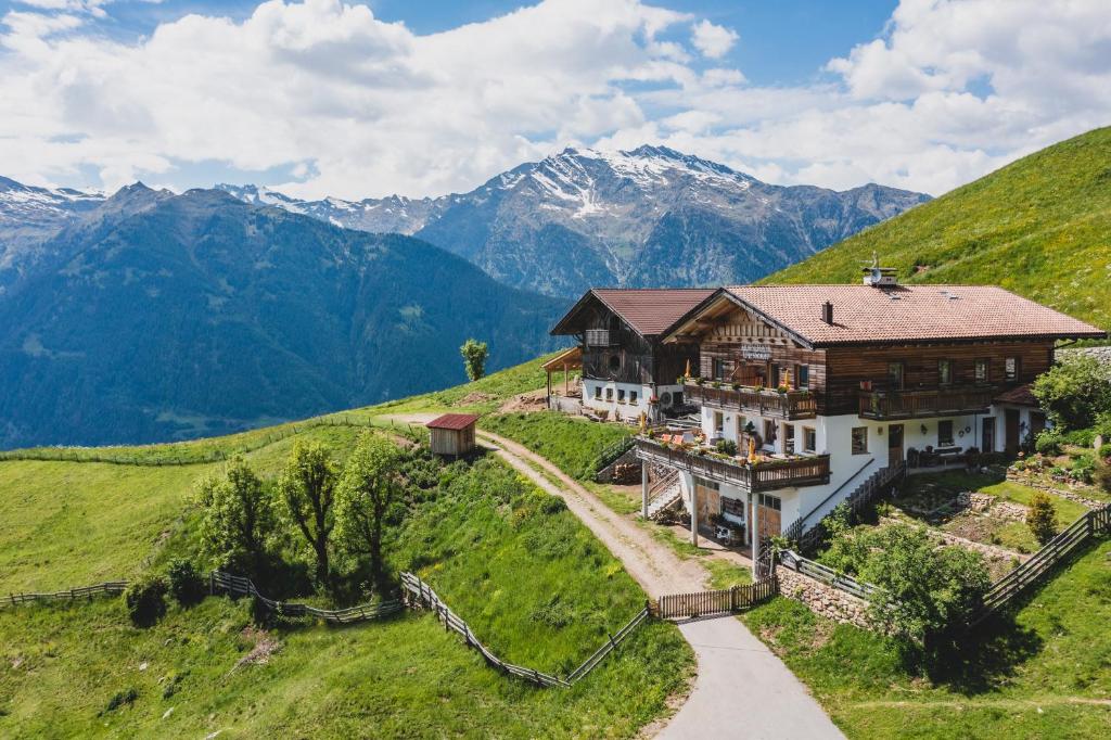 uma casa numa colina com montanhas ao fundo em Ferienwohnungen Wiesbauer em Scena