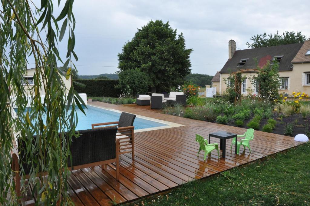 eine Holzterrasse mit Stühlen und einem Tisch neben einem Pool in der Unterkunft GITE AU BIEN AITRE in Beaumont-Pied-de-Boeuf