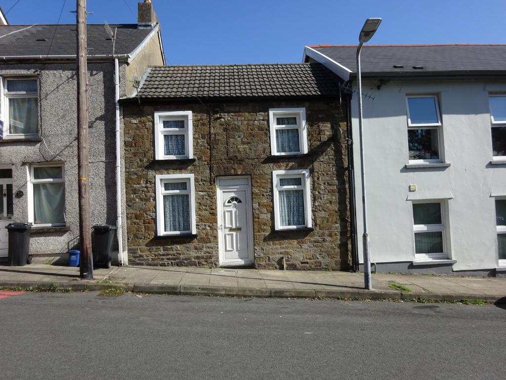 a brick house with a white door on a street at Charming Cottage style 3 bedroom property in Merthyr Tydfil