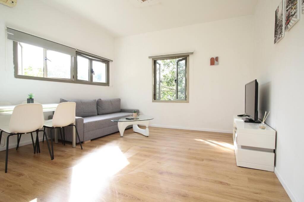 a living room with a couch and a table and a tv at Peaceful Apartment Next To Gordon Beach By Vacay in Tel Aviv
