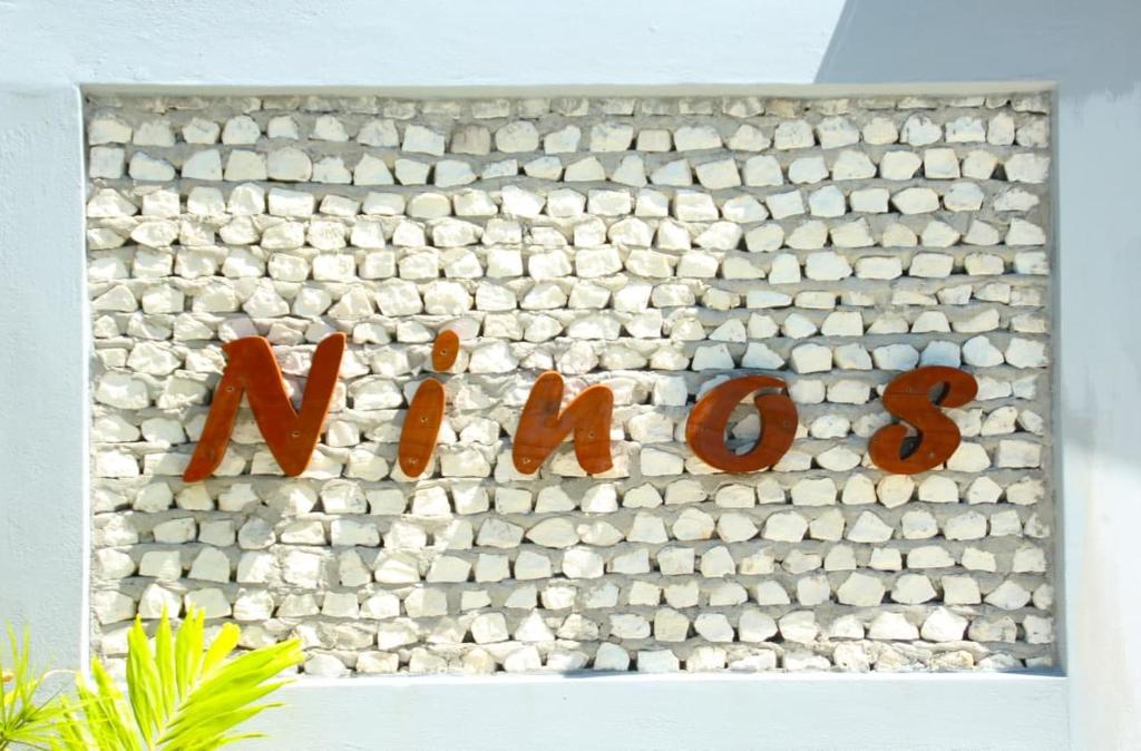 a stone wall with a sign that says newizons at Ninos K.Guraidhoo in Guraidhoo