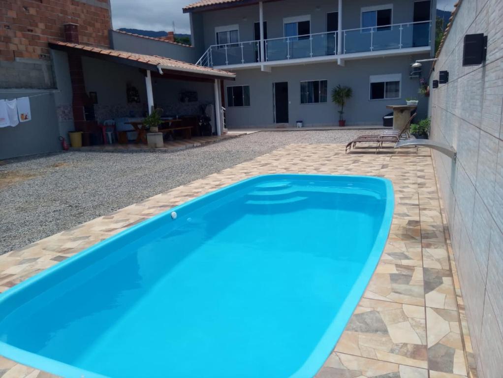 a large blue swimming pool in front of a house at Casa nova com piscina próxima a praia e menos de 3km do centro de Ubatuba in Ubatuba
