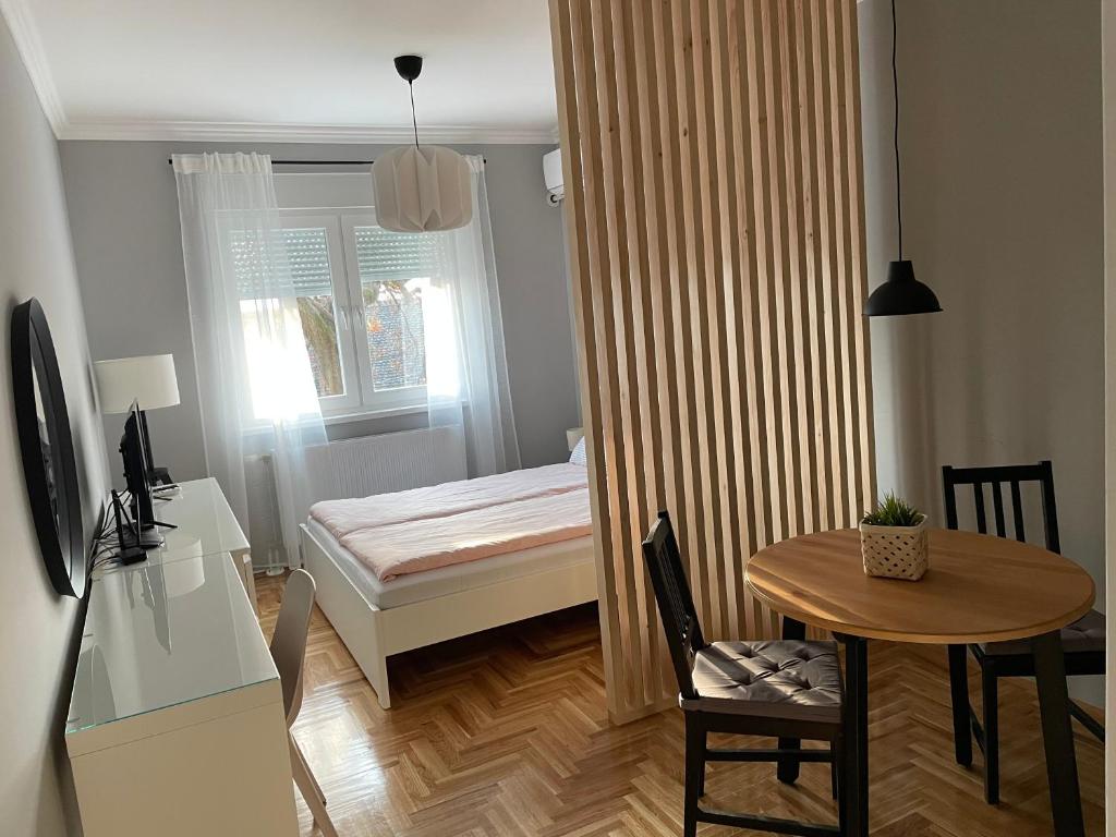 um pequeno quarto com uma pequena mesa e uma cama em Apartmani Sombor em Sombor