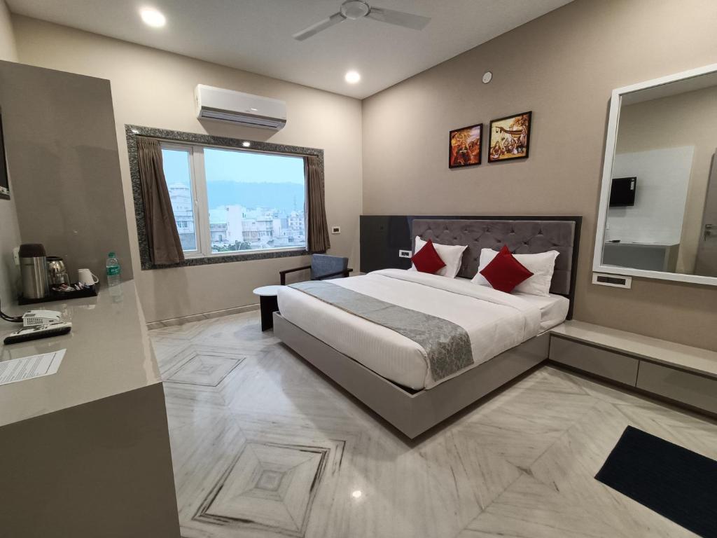 ein Schlafzimmer mit einem großen Bett und einem großen Fenster in der Unterkunft Hotel Shri Anand Dham, Nathdwara - 125 Meters away from the temple in Nāthdwāra