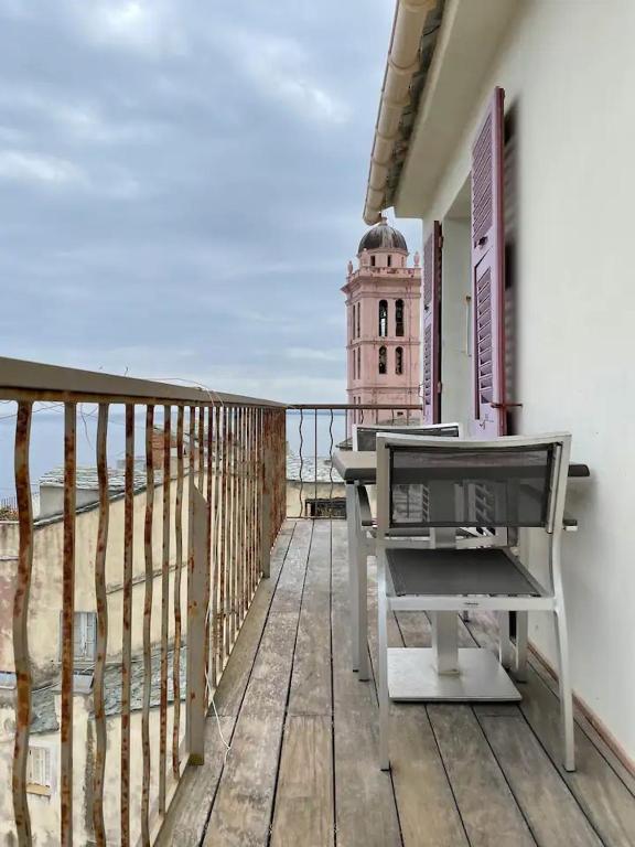 a balcony with a table and a clock tower at CASA GUASCO superbe duplex au cœur de la Citadelle, vue à 360 in Bastia