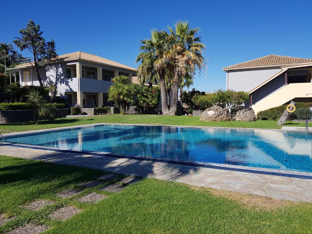 a swimming pool in front of a house at Asteraki ApartHotel in Gouvia