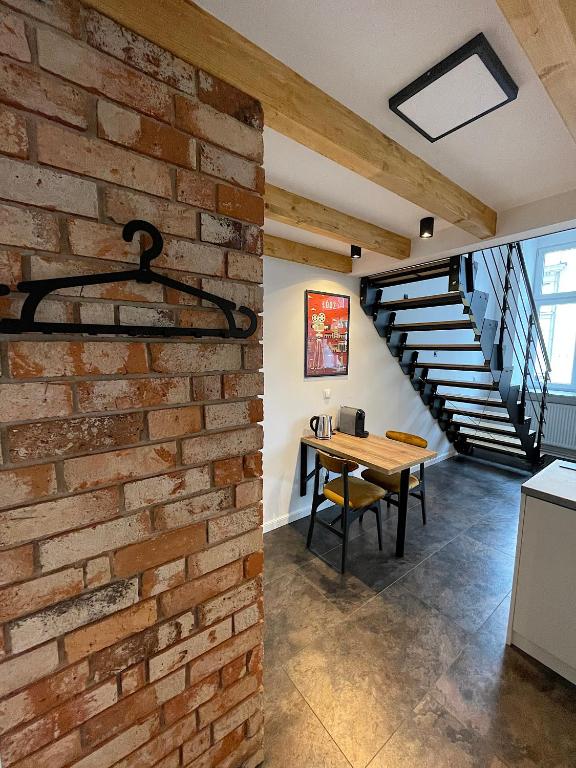 a brick wall in a kitchen with a table and a staircase at OFF Side Story Apartment in Łódź