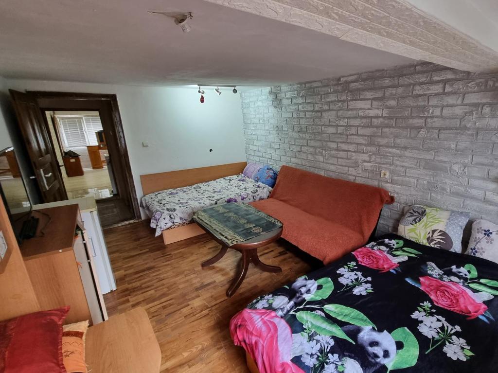 ein Wohnzimmer mit Sofa und Ziegelwand in der Unterkunft 2 стаен до парка in Razgrad