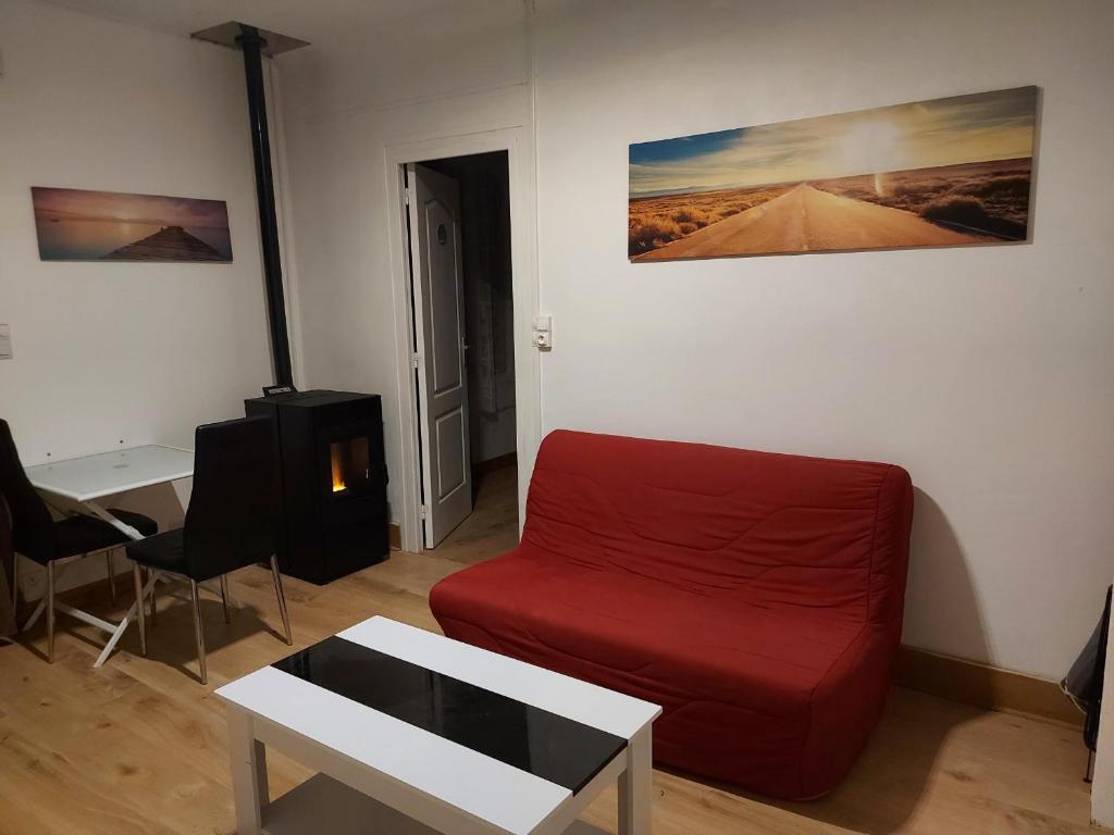 a living room with a red couch and a table at Le studio d Olivia in Avallon