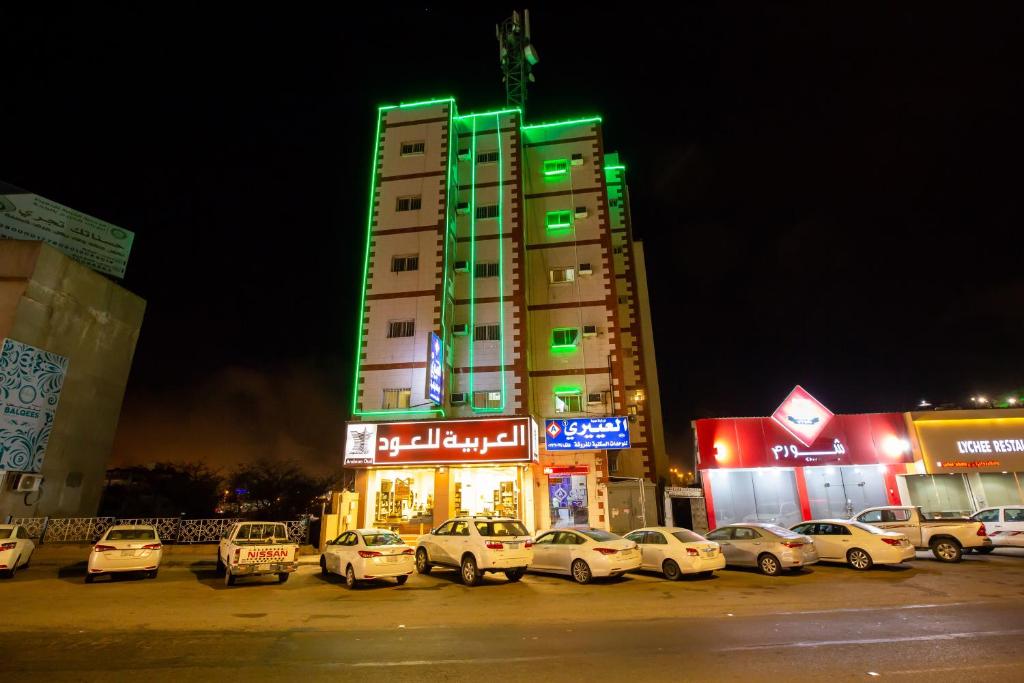 ein hohes Gebäude mit Autos auf einem Parkplatz in der Unterkunft العييري للوحدات المفروشة الباحة 1 in Al Bahah
