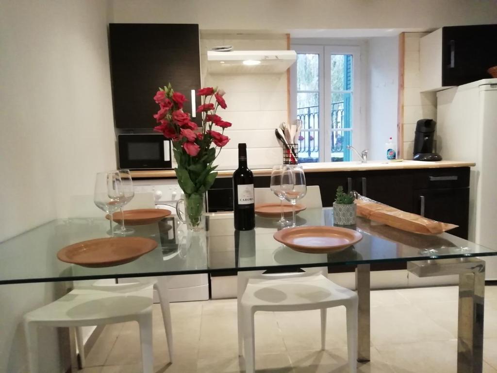 una cocina con una mesa de cristal con una botella de vino y flores en L'éden Quercynois, en Souillac